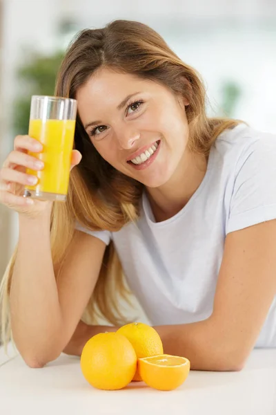 快乐的女人拿着橙汁看着相机 — 图库照片