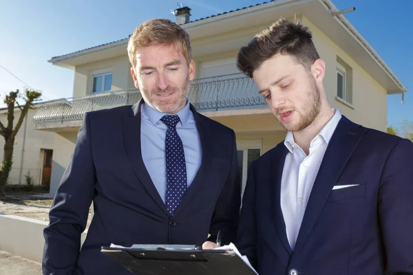 suited men with clipboard outside a residential property