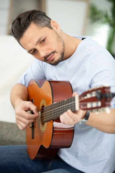 Jovem Bonito Tocando Guitarra Enquanto Sentado Sofá — Fotografia de Stock