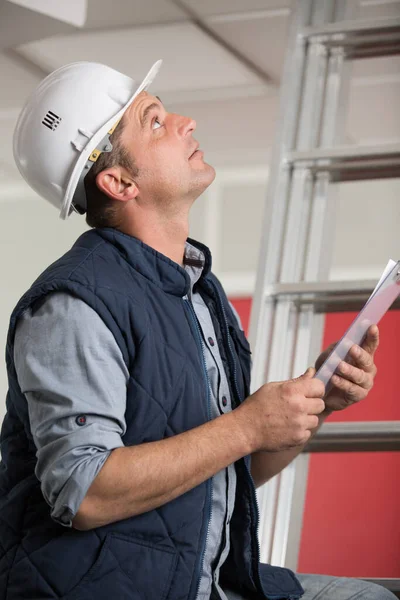 Trabajador Escribiendo Portapapeles Mientras Mira Techo —  Fotos de Stock