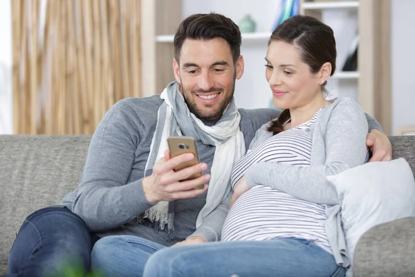 Mulher Grávida Homem Bonito Sofá Usando Smartphone — Fotografia de Stock