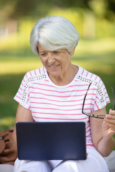 Mogen Kvinna Sitter Parkbänk Med Bärbar Dator — Stockfoto