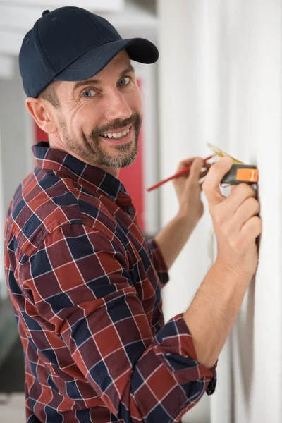 Homem Feliz Medindo Parede Com Uma Fita Métrica — Fotografia de Stock