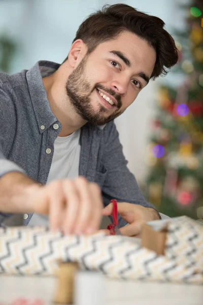 Молодой Человек Заворачивает Рождественский Подарок — стоковое фото