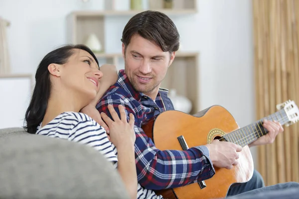 Kanepede Gitar Çalan Erkek Arkadaşı Dinleyen Bir Kadın — Stok fotoğraf