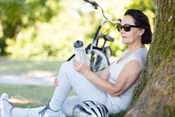 Senior Kvinnlig Cyklist Som Vilar Lutande Sig Mot Ett Träd — Stockfoto