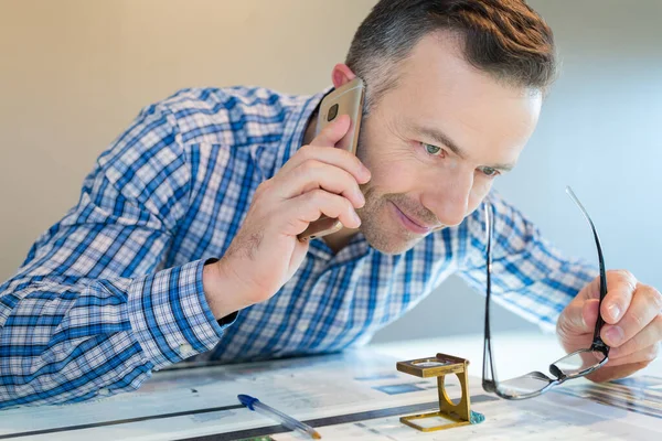 Uomo Alla Scrivania Con Dispositivo Ingrandimento Che Parla Smartphone — Foto Stock