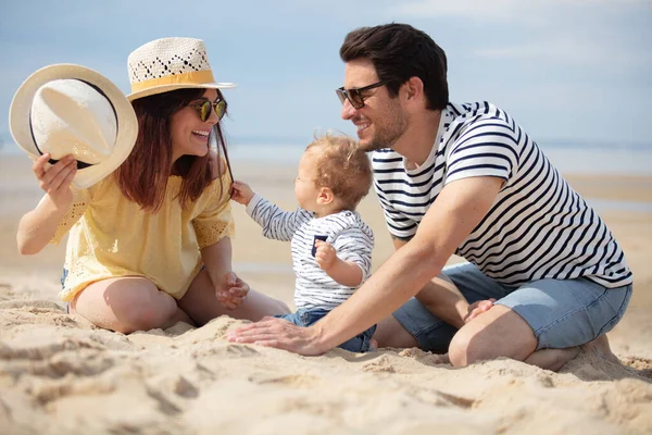 一个快乐的家庭带着一个小孩在海滩上 — 图库照片
