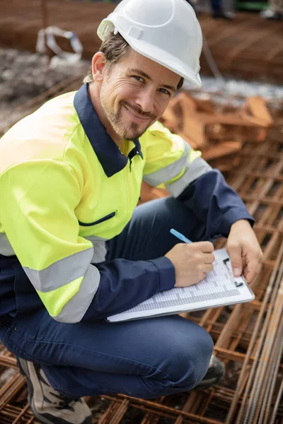 Werknemer Met Klembord Hurken Stapel Rebars — Stockfoto