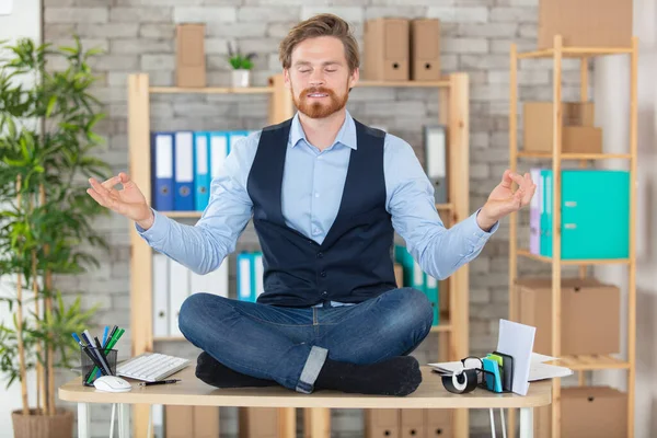 zen businessman doing yoga meditation on office desk