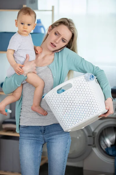 洗濯機に衣類を積み込む母親と赤ちゃん — ストック写真