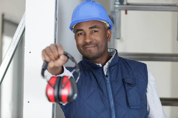 Jovem Construtor Oferecendo Auriculares Para Câmera — Fotografia de Stock