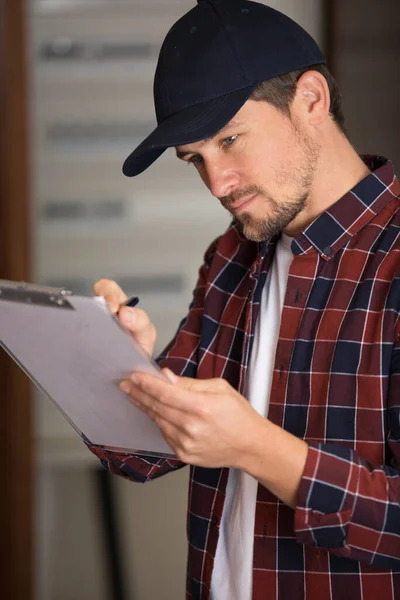 Elektricien Kijkt Naar Zekeringkast Met Klembord — Stockfoto