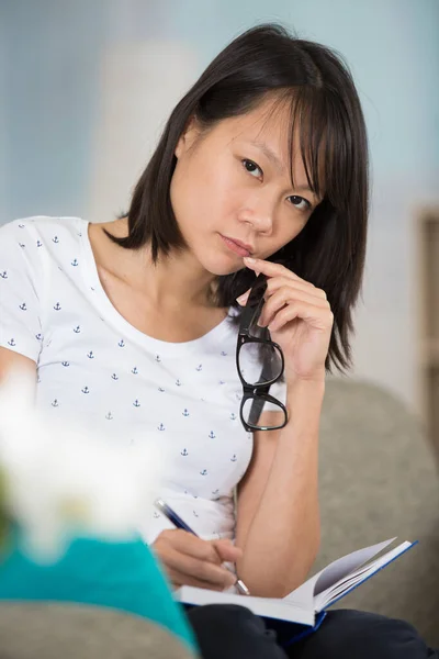 沉思的女人在笔记本上写字 — 图库照片