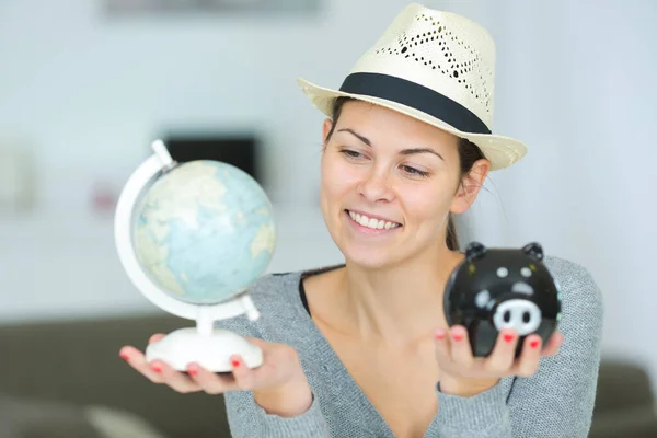 头戴太阳帽的女人拿着地球仪和储蓄罐 — 图库照片