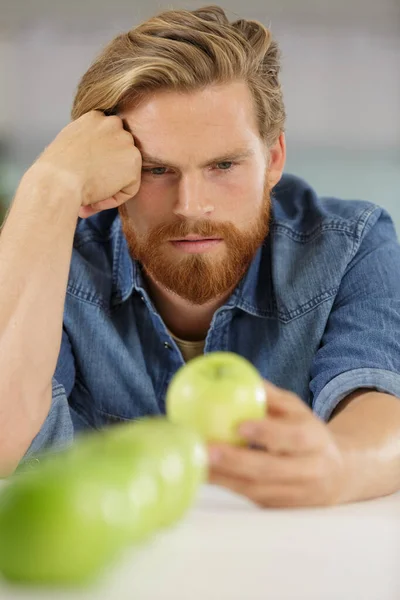 Düşünceli Genç Adam Yeşil Elmayı Gözlemliyor — Stok fotoğraf