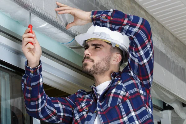 Giovane Costruttore Utilizzando Cacciavite Sul Muro — Foto Stock