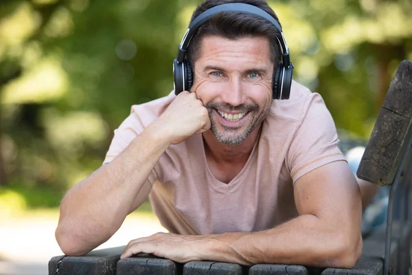 Junger Mann Mit Kopfhörern Liegt Auf Einer Parkbank Freien — Stockfoto