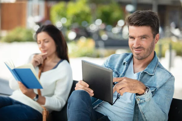 Hombre Usando Una Tableta Mujer Con Libro Aire Libre — Foto de Stock