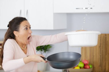 worried woman holding bucket while water droplets leaking from ceiling clipart