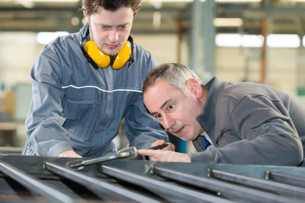 Twee Industriearbeiders Die Een Werkstuk Inspecteren Dat Grond Staat — Stockfoto