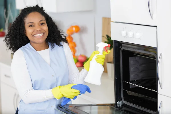 快乐的女人用喷雾器和海绵清洗烤箱 — 图库照片