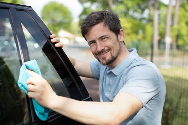 マイクロファイバーの布で車を掃除する男 — ストック写真