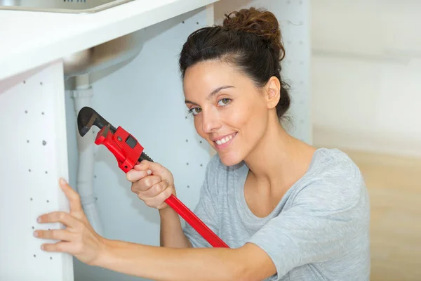 Mujer Sonriente Usando Llave Inglesa Debajo Del Fregadero Cocina — Foto de Stock