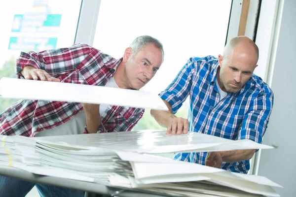 Άνδρες Στην Επιχείρηση Εκτύπωσης Κοιτάζοντας Μέσα Από Πλαστικά Αντίγραφα — Φωτογραφία Αρχείου