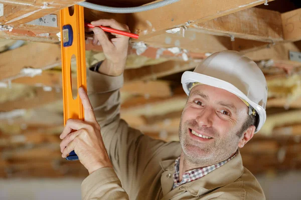成熟的男性建筑工人在天花板上使用灵气水平 — 图库照片