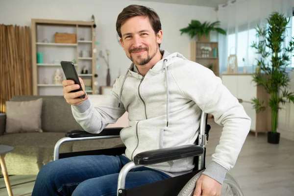 Vrolijke Man Een Rolstoel Thuis Met Smartphone — Stockfoto