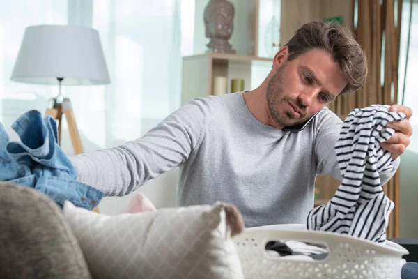 Man Sortera Tvätt När Pratar Smartphone — Stockfoto