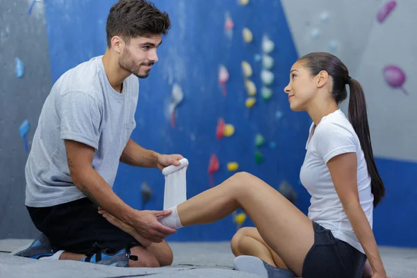 trainer wrapping bandage on a female wall climber