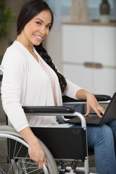 happy disabled woman in wheelchair at home with tablet pc
