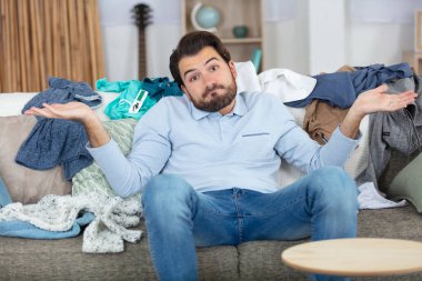 young man not happy to do the laundry clipart