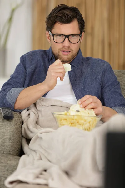 happy man eating popcorn and watching tv at home