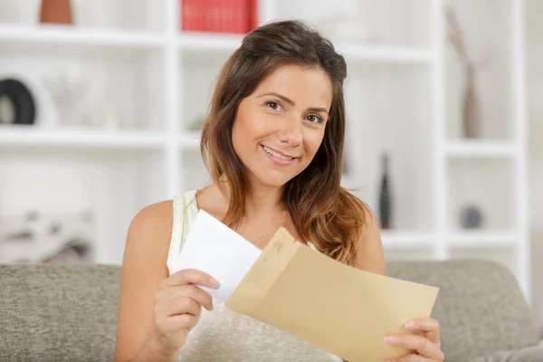 Hermosa Chica Sonriente Sentada Sofá Sosteniendo Sobre — Foto de Stock