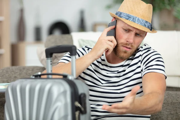 stressed man on telephone pointing to his suitcase