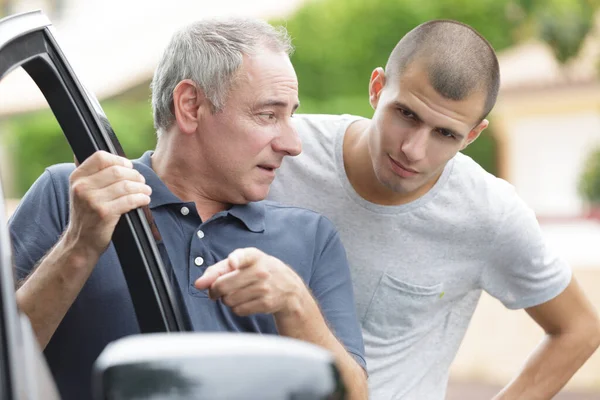 Mature Man Talking Teenage Boy Getting Car Royalty Free Stock Photos