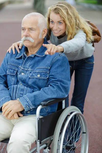 坐在轮椅上的女儿和父亲指着什么东西 — 图库照片