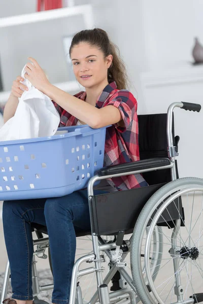 Giovane Donna Vestiti Pieghevoli Dalla Sua Sedia Rotelle — Foto Stock