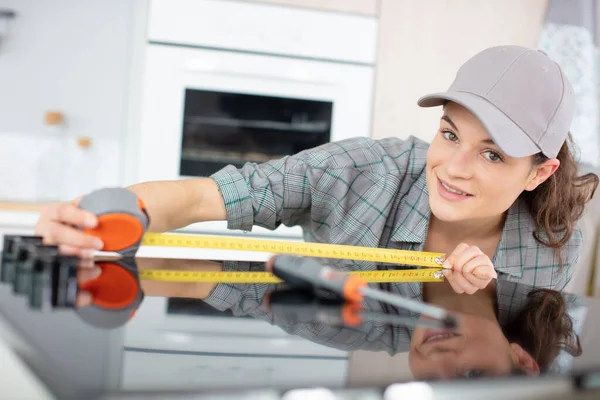 Young Repairwoman Measuring Width Kitchen Stove — Zdjęcie stockowe