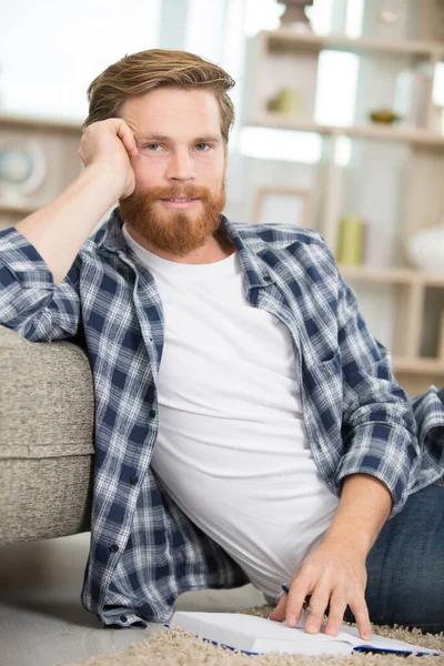 Knap Blond Man Liggend Tapijt Met Een Boek — Stockfoto