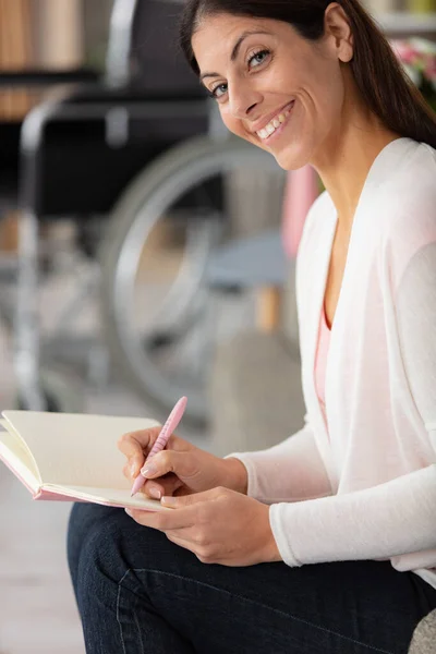 Frau Schreibt Buch Mit Rollstuhl Hintergrund — Stockfoto