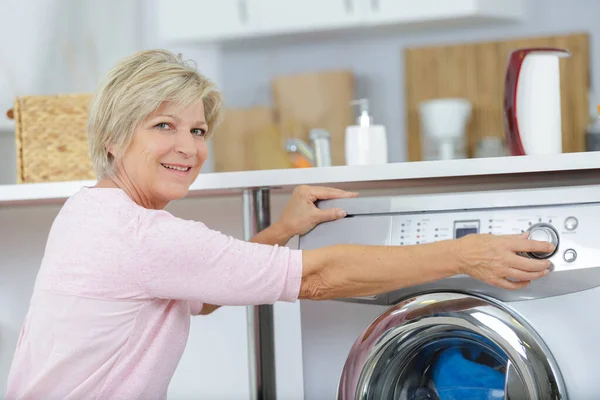 Mulher Sênior Colocando Máquina Lavar Roupa — Fotografia de Stock