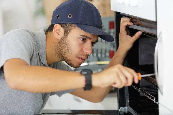 Young Serviceman Working Oven Using Screwdriver — Foto de Stock