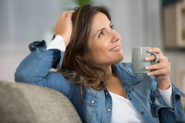 Femme Souriante Assise Sur Canapé Tout Buvant Thé — Photo