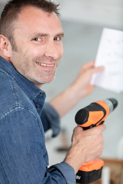 casual man reading instruction manual for power tool