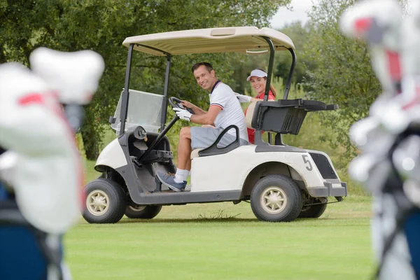 这对笑容可亲的夫妇开着一辆高尔夫球车 — 图库照片