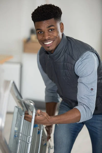 Alegre Joven Hombre Llevando Escalera —  Fotos de Stock